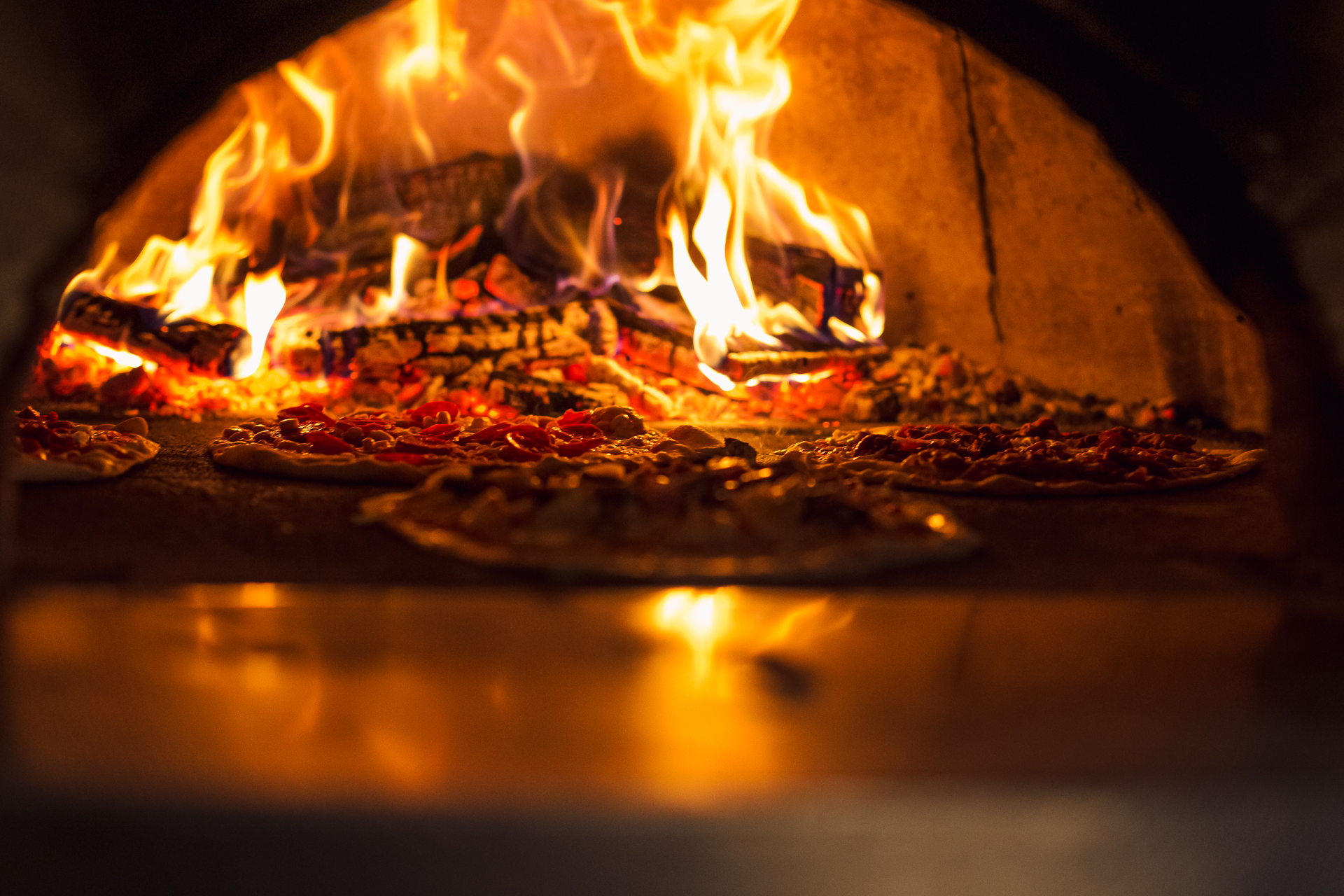 wood fire pizza coming out of the oven